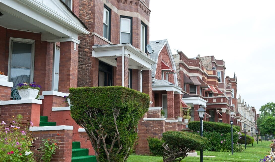 Photo of red brick houses and green lawns looking across the block