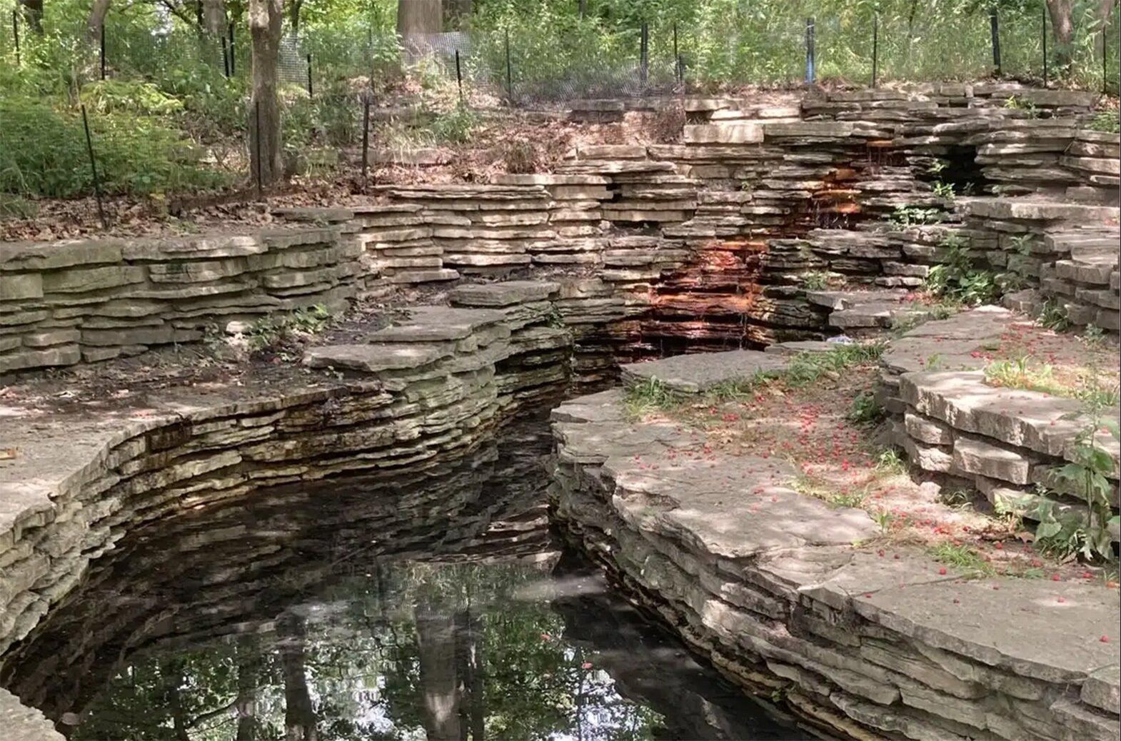 A stream lined with  stacked flat rocks and greenery