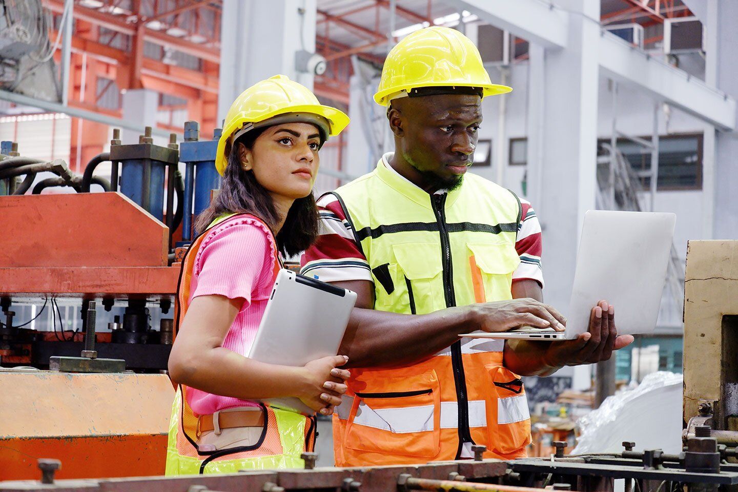Male and female young adult with construction hats in a warehouse
