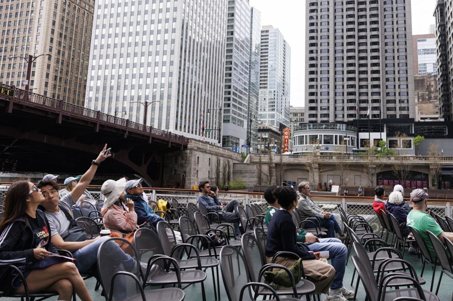People sitting in chairs on a boat deck looking up and pointing