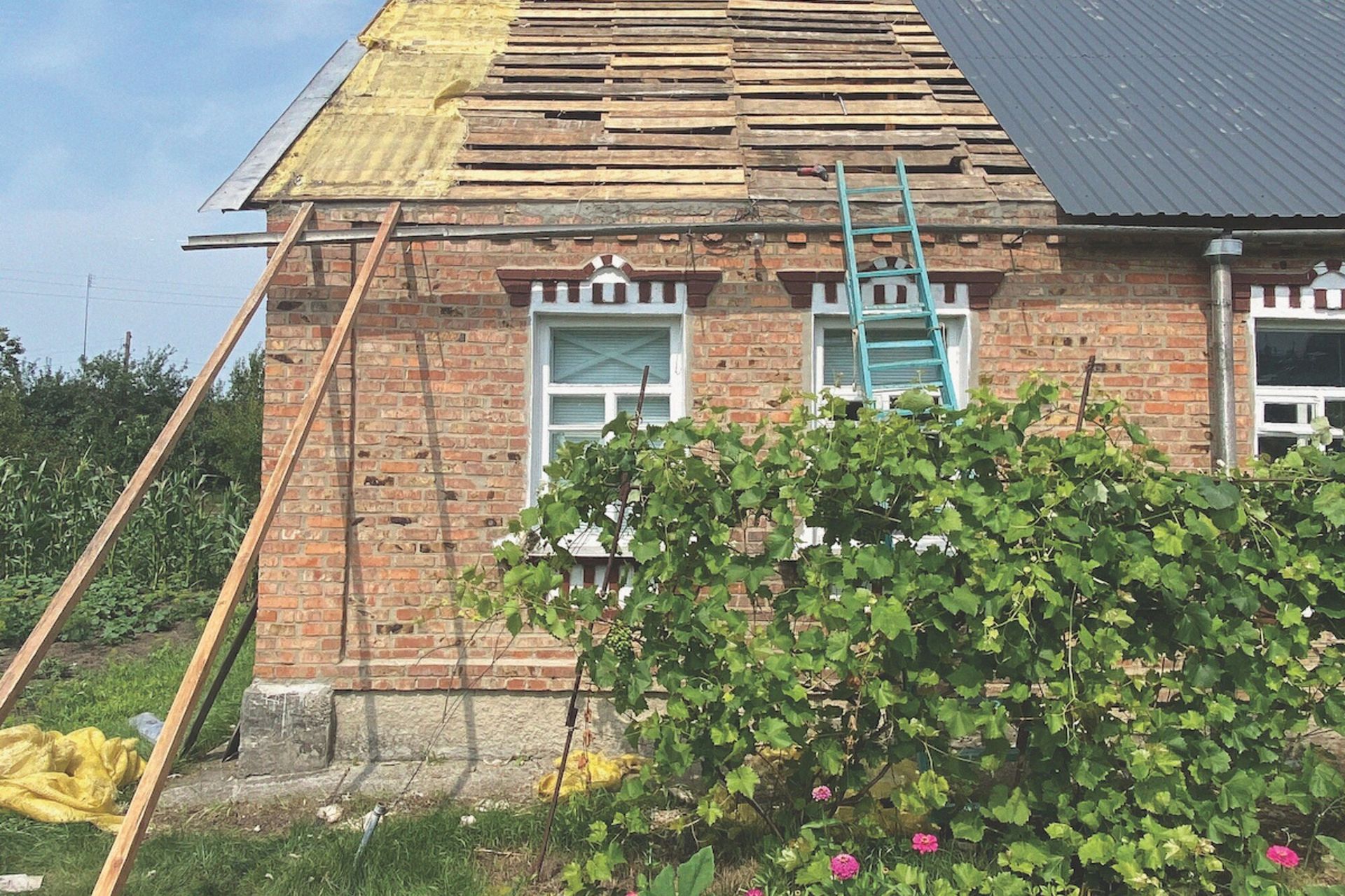 Image of a brick building with a partially complete roof. Ladders lean against the building.