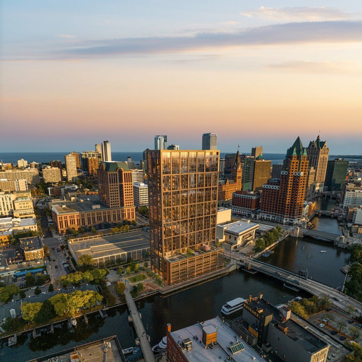 Image of a large rectangular tower set next to a bridge on a river surrounded by other buildings.