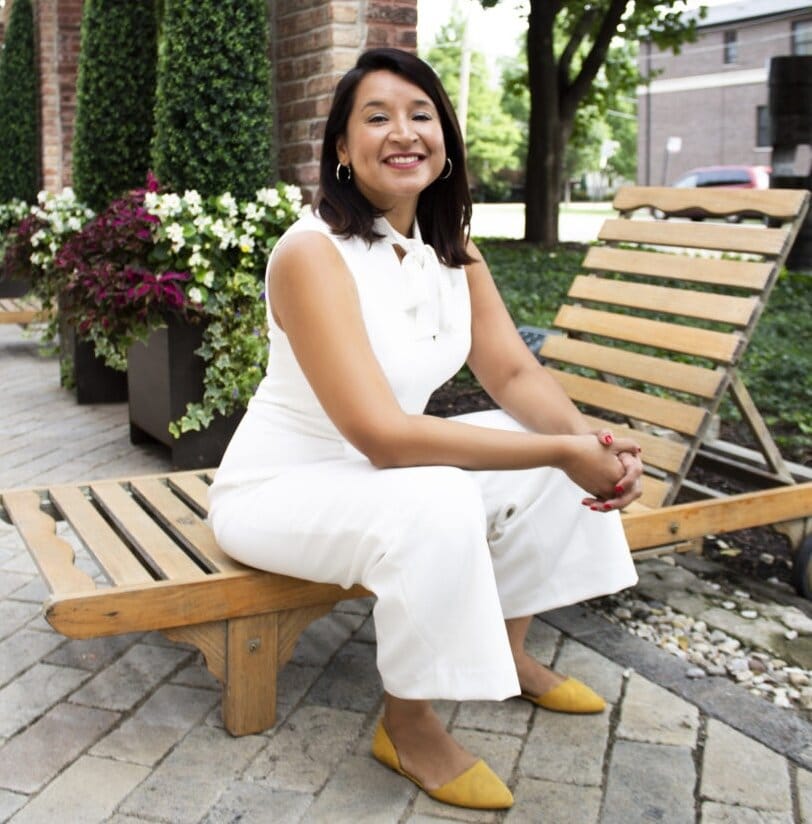 A woman sitting on a lounge chair outside.
