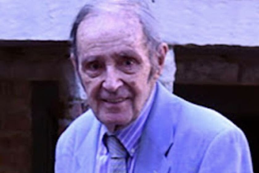 Image of a man with gray hair in a blue suit and tie