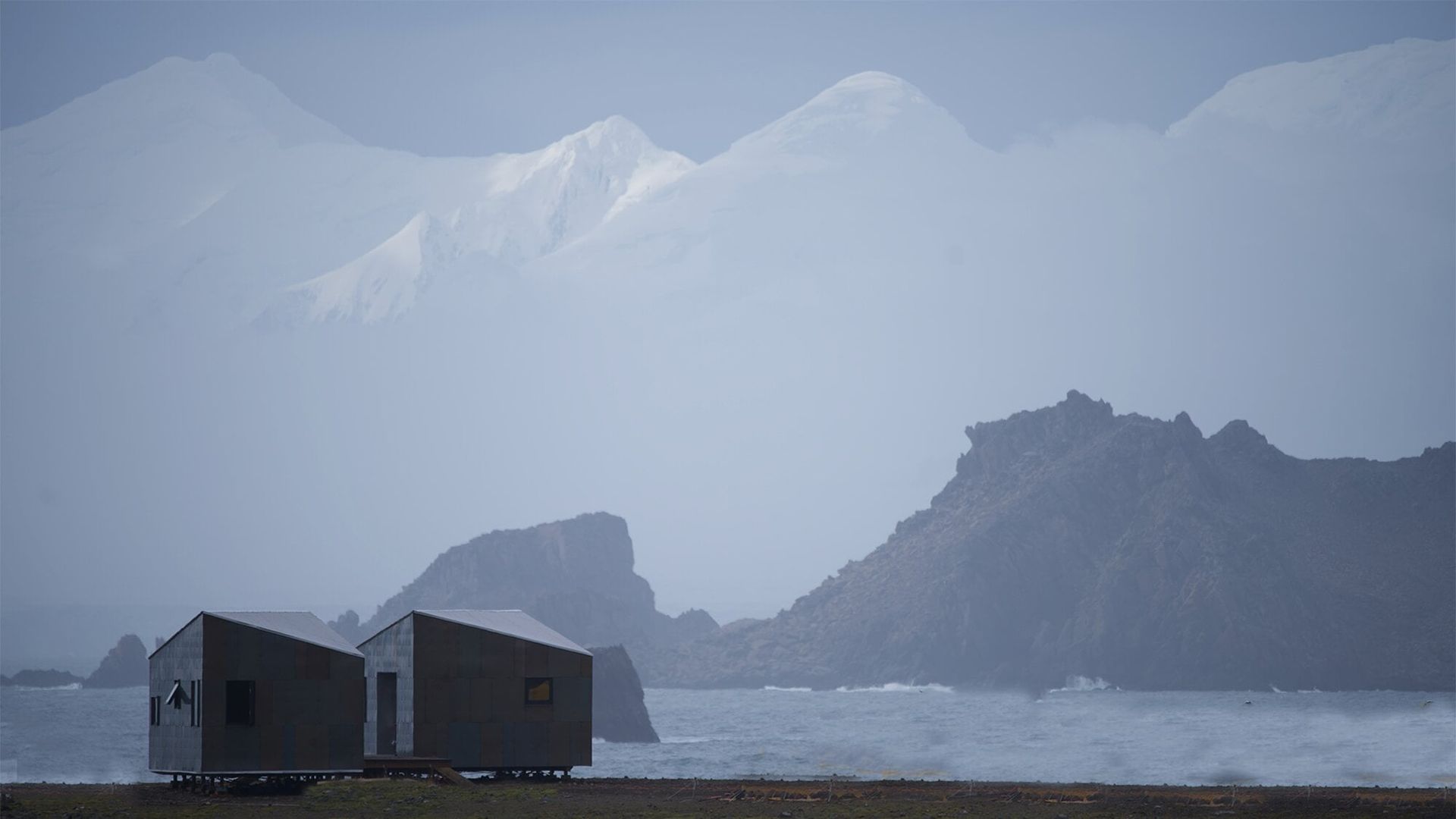 Grey outdoor scene of two small houses amidst a vast grey outdoors