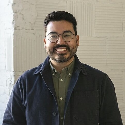 A man smiling with glasses and a jacket.