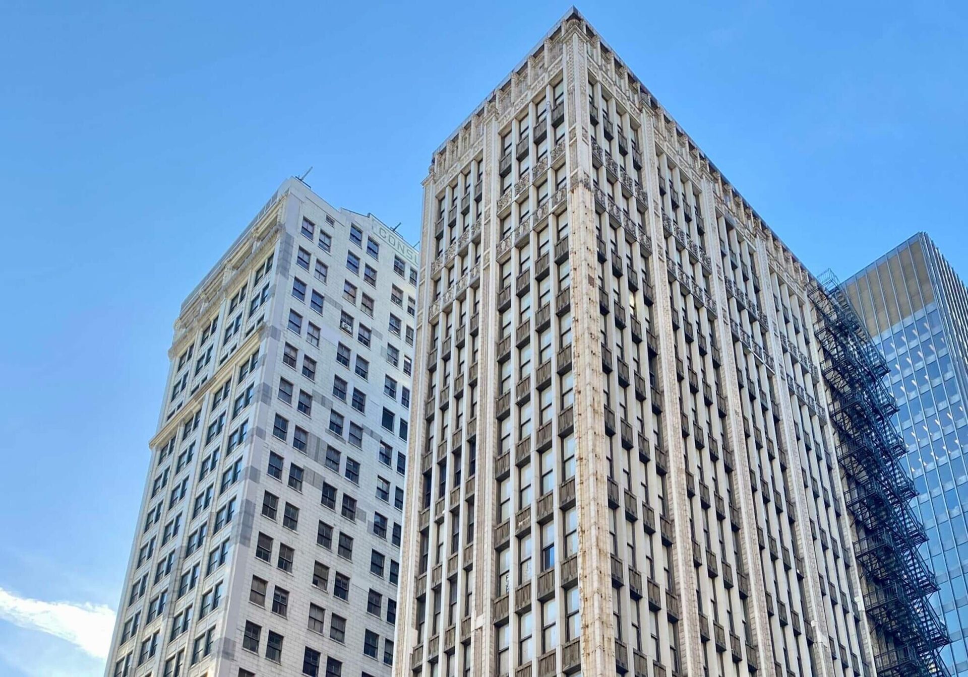 Image of two tall white skyscrapers side by side with a tall black building behind them. 