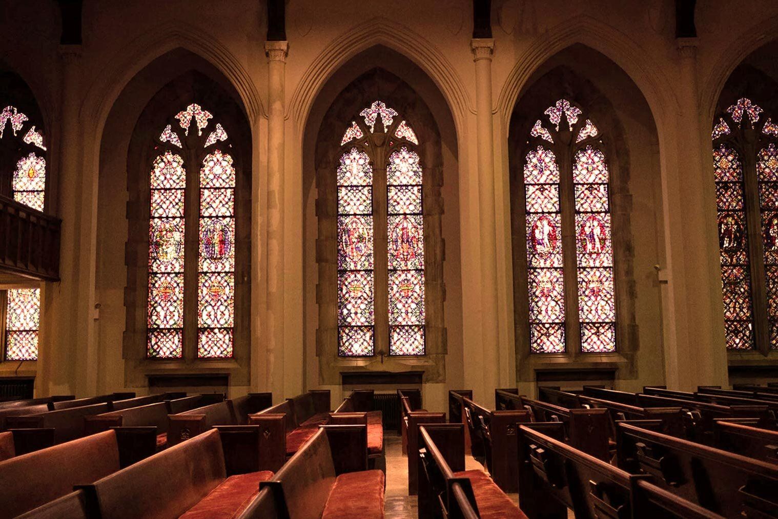 Interior of a church with pews and stained glass windows.