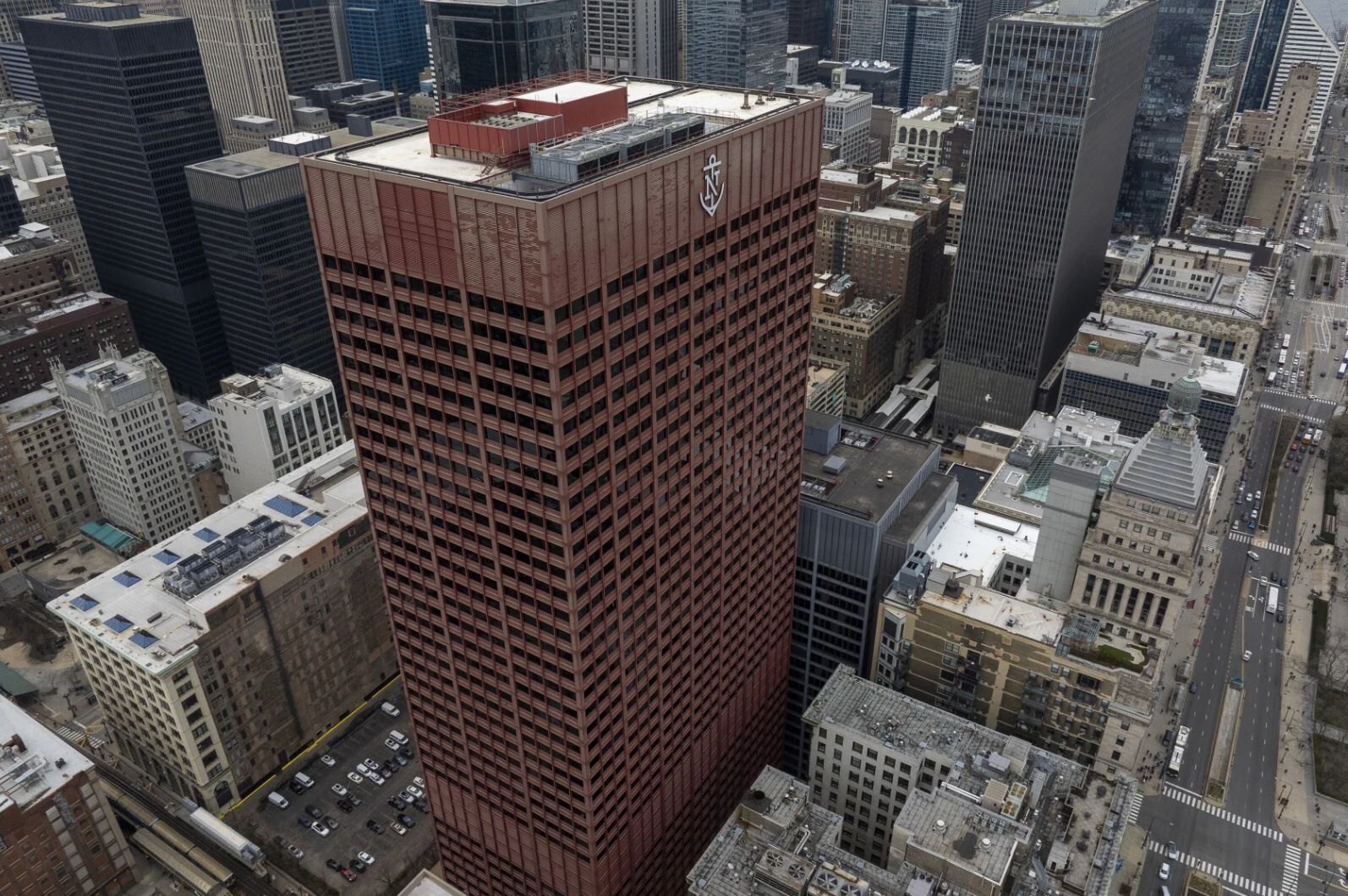 Aerial view of a red skyscraper among shorter buildings.