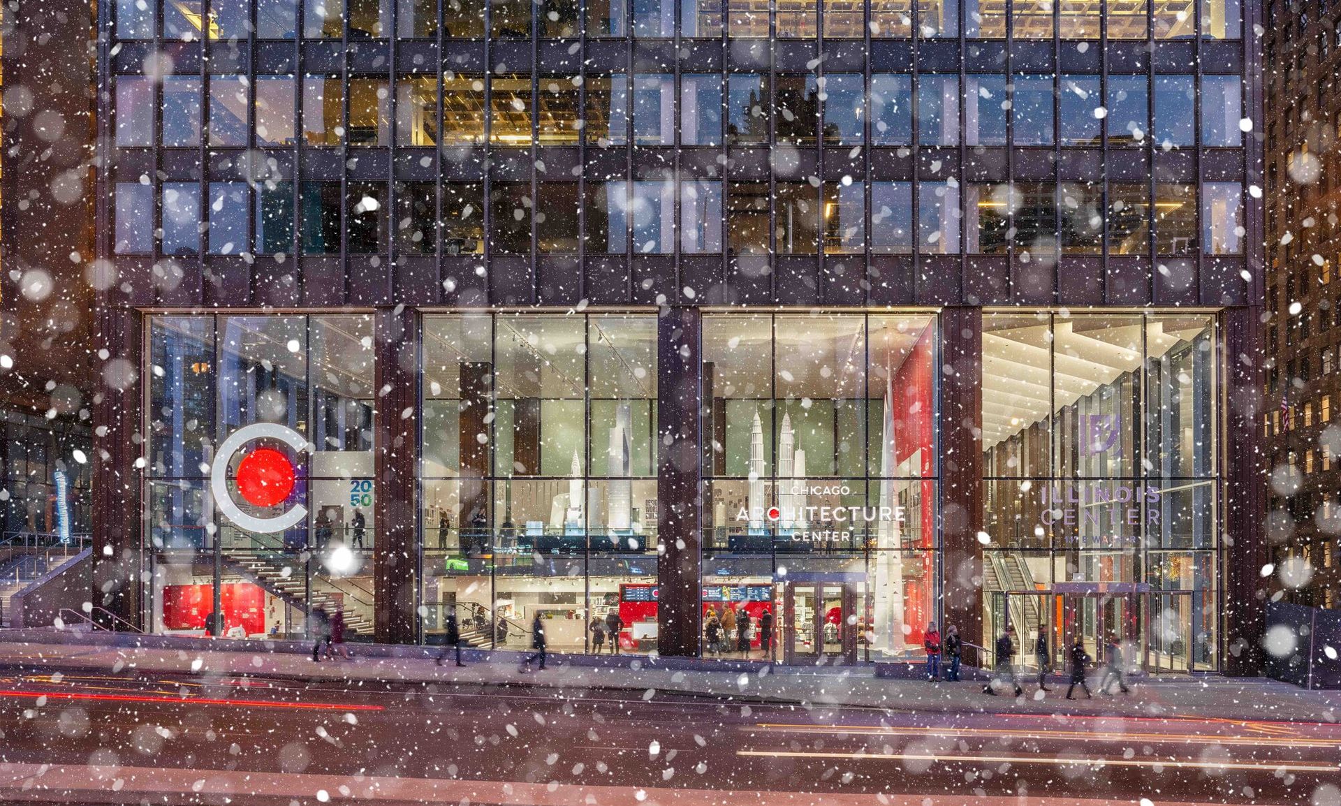 Image of a black builing with large windows taking up the first two floors. There is a logo on the front of the letter "C" with a red circle inside of it. It is snowing outside.