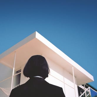 The back of a woman's head looking toward a pointed roof.