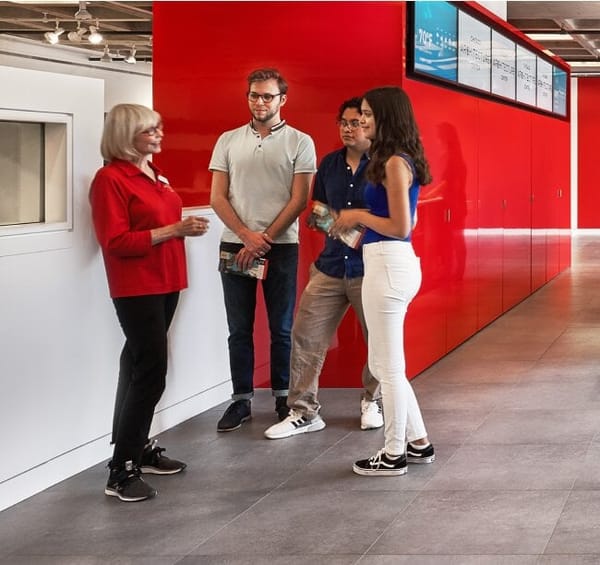 4 people in front of a red wall. 