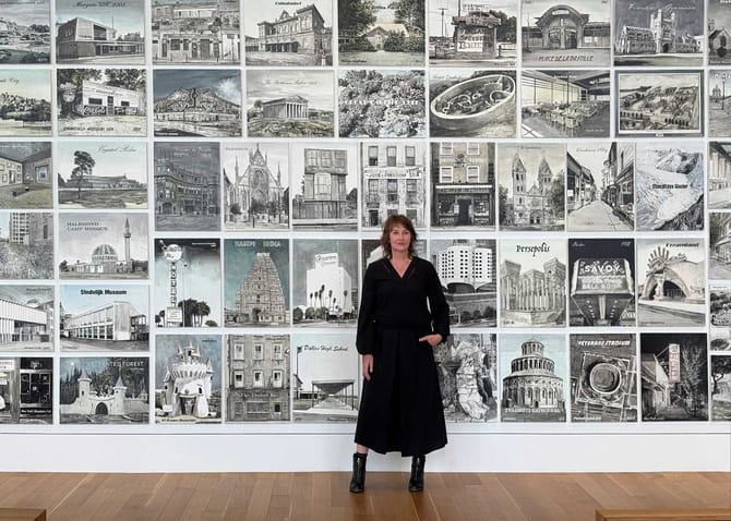 Woman in black costume standing in front of a wall of black and white paintings