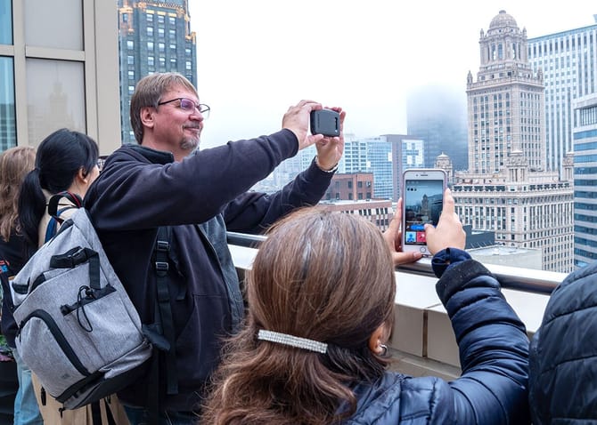 A few people looking out of a rooftop taking photos of an ornate building