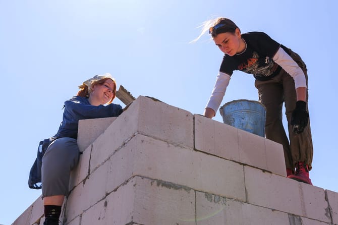 Two women climbing and building with bricks