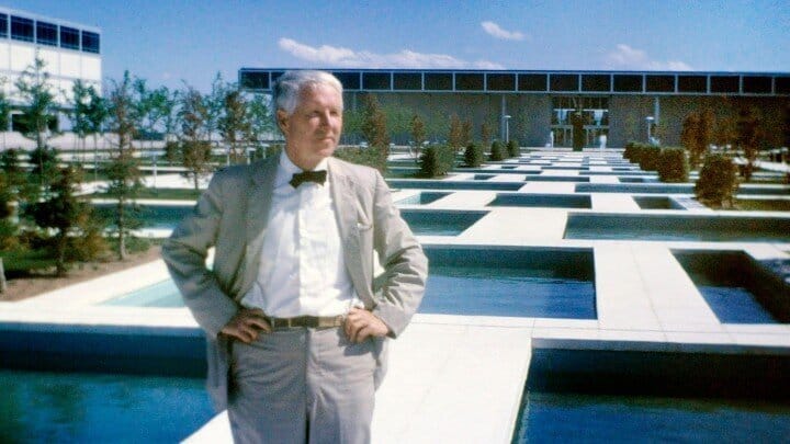 A white man in a bow tie in front of a large plaza