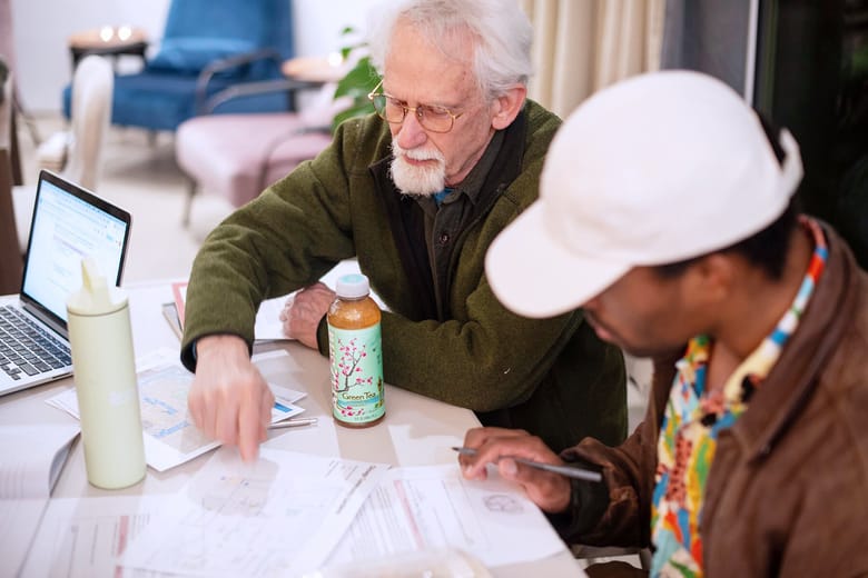 Two men seated and working on a project together