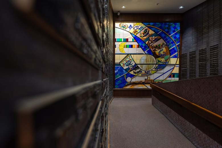 Interior image of a building with a stained glass wall. 