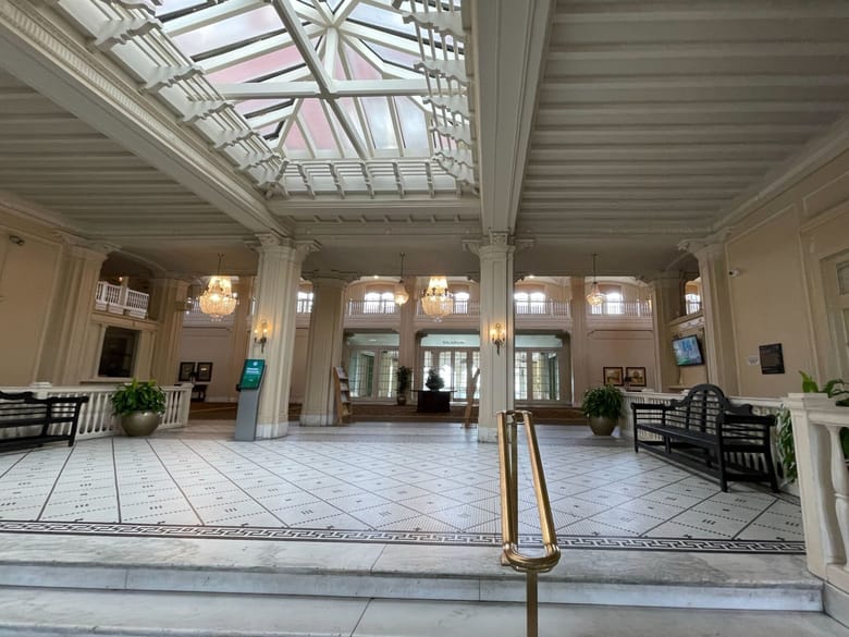 Interior image of a lobby with stairs in the foreground with a glass ceiling.
