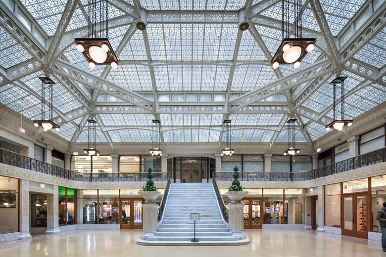 Interior view of the Rookery Building in Chicago, featuring a grand atrium with ornate ironwork, marble floors, and natural light.