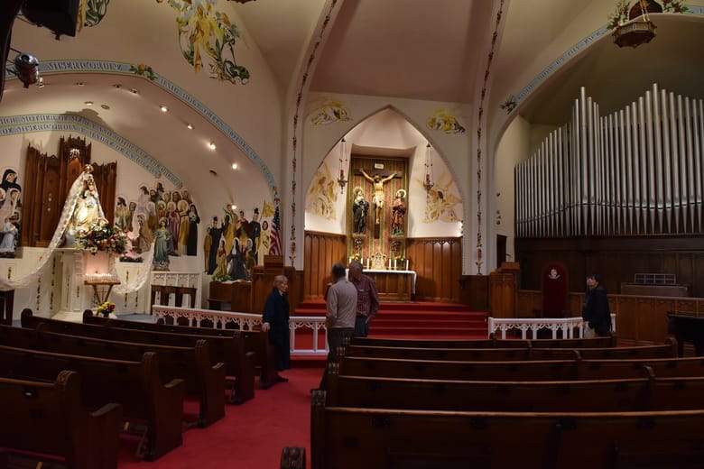 Interior of a church with red carpet and brown benches.