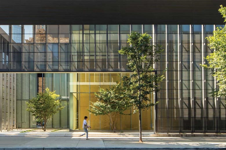 Image of a building entry with a glass facade and trees out front.
