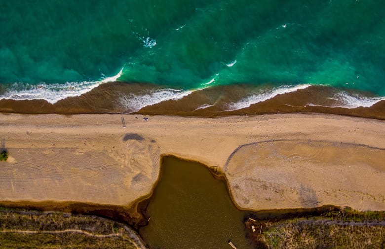 Aerial view of a body of water and sand on a beach.