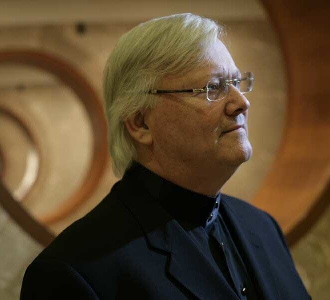 Image of a caucasian man with white hair and glasses.