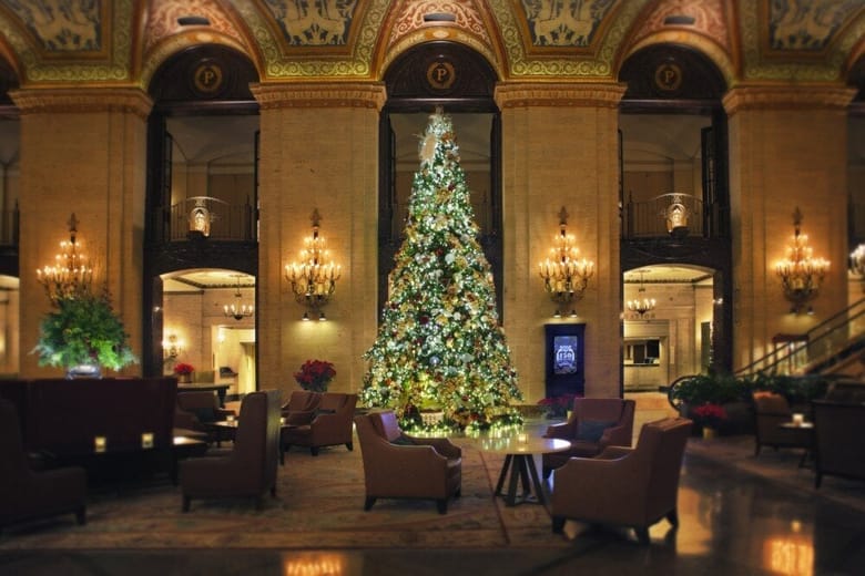 Hotel interior showing a painted ceiling, a staircase, and golden light fixtures and a Christmas tree in the center