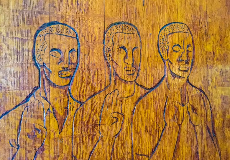 Image of wood with figures carved into it. 
