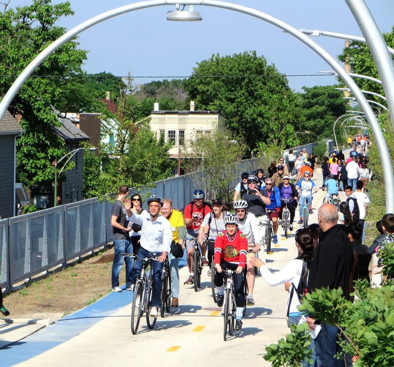 Group of bikers with helmets riding on elevated bike path with in the daytime.