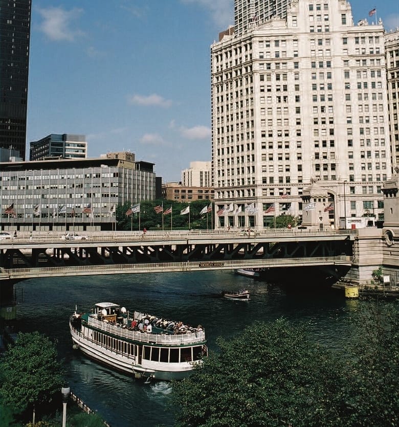 Skyscrapers on a river with a boat on the water.