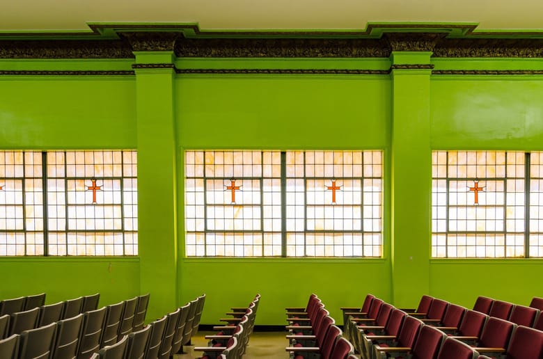 Image of a building interior with stain glass windows and lime green walls.