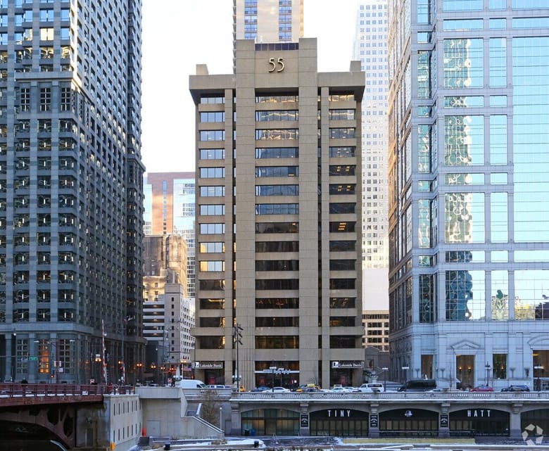 A tall concrete building with the number 55 in gold at the top of the face of the building.