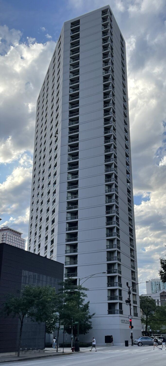 Image of a tall gray trapezoid shaped building. 