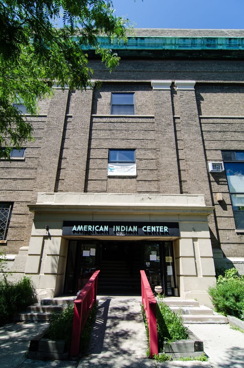 Facade of a brown brick building and front door with a sign above that reads "American Indian Center"