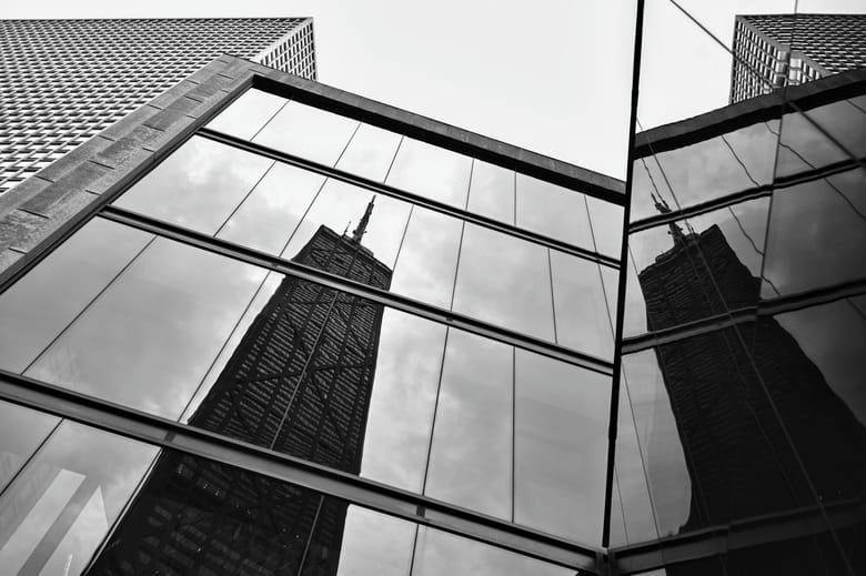 Black and white photo of a building reflecting the silhouette of another building