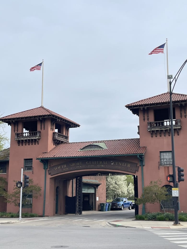 Two red brick towers on either side of an entrance with flags on their rooftops. 