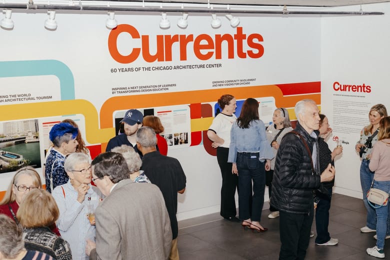 People standing in front of an exhibition wall that says "currents". 