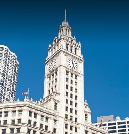 Exterior of tall white building with pointed roof and blue sky