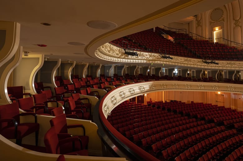View from the stage of a concert hall with a harp in the middle of the stage and looking out into the empty seats. 