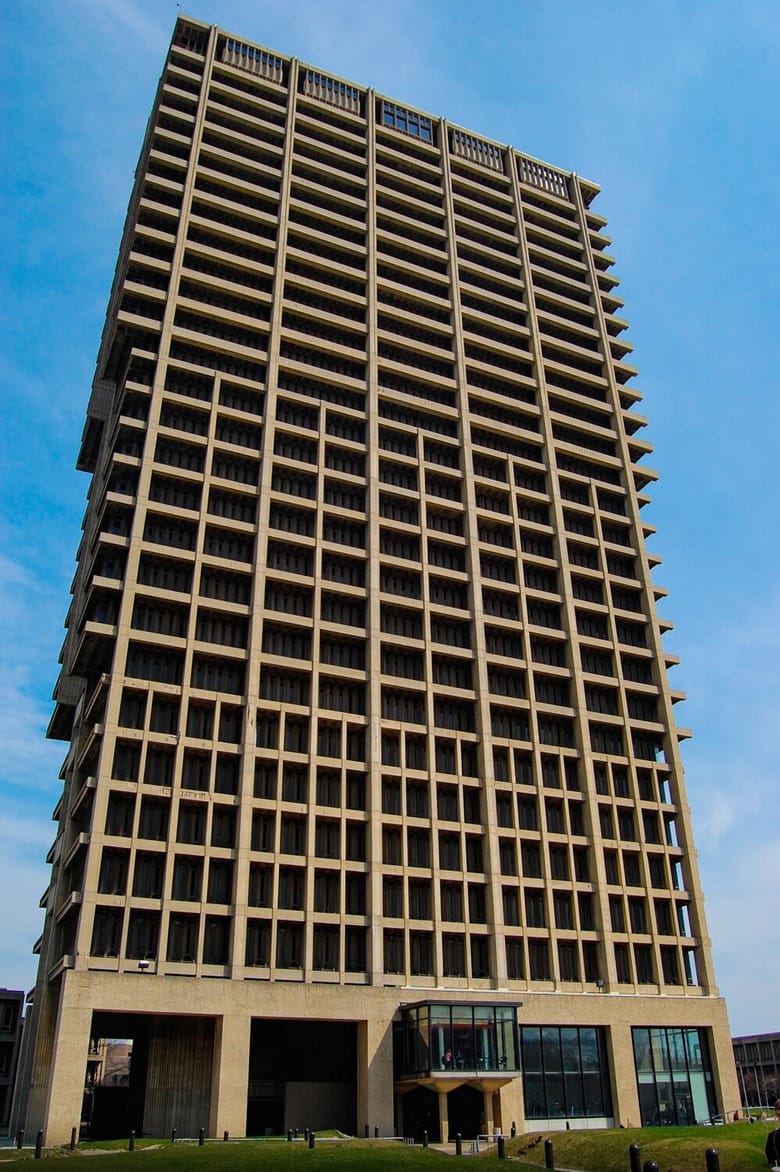 Image of a tall concrete building with lots of visual lines and recessed windows. 