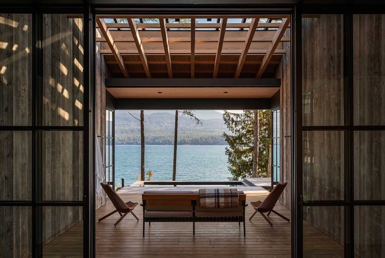 Wood-clad lakeside retreat with open-air living space overlooking water and forest.