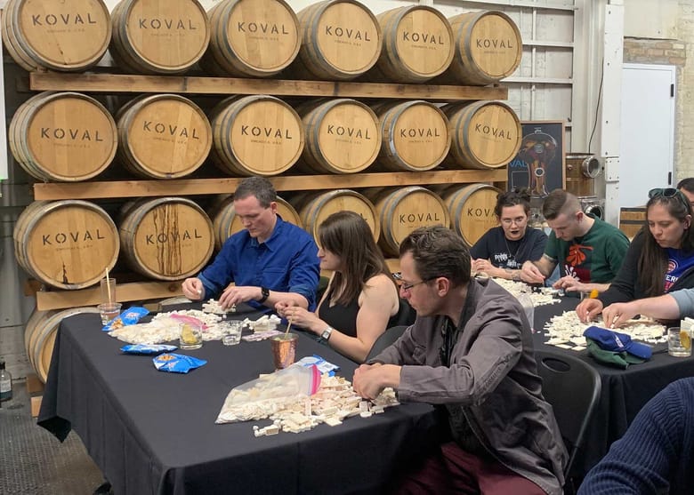 People seated working on a lego build with beer barrels in the background