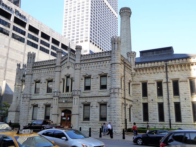 Large stone building with skyscrapers in the background.