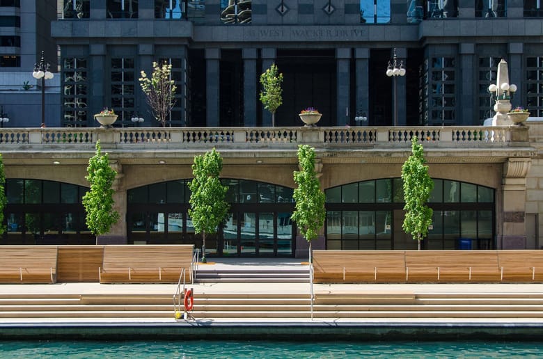 Wide steps leading down to a river in front of a building with large arched glass windows. 