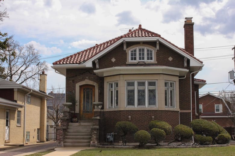 Image of a small red brick bungalow style house with orange tiled roof.