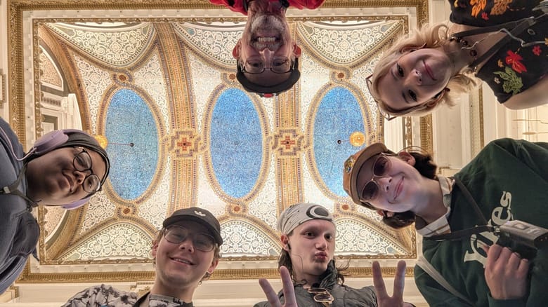 A group of people pose with the Tiffany glass ceiling at Macy's on State Street