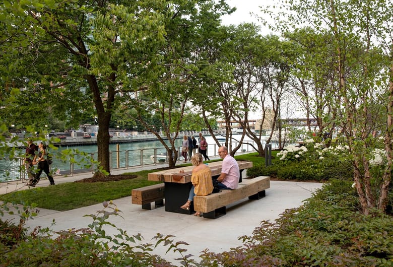 People sitting at a picnic table on the river. 
