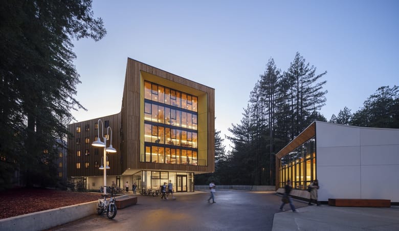 Wooden and glass building in the woods at dusk.